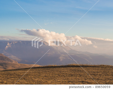 Clouds float on a plateau located in the distance in the mountain valley of the Caucasus 89650059