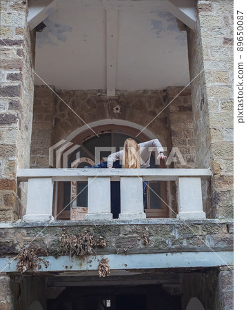 A shaggy scary woman climbs over the balcony of an old abandoned castle. Mystic idea. The ghost of an old forest house A shaggy scary woman climbs over the balcony of an old abandoned castle. Mystic idea. The ghost of an old forest house 89650087