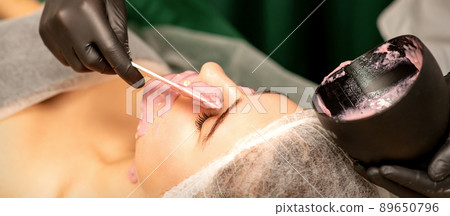 Beautiful young caucasian woman receiving an alginic mask to the face in beauty salon. Facial skin treatment 89650796