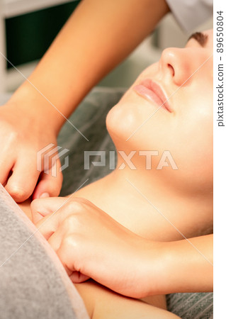 Massaging female breast, and shoulder. Young beautiful caucasian woman receiving chest and shoulders massage in beauty spa salon 89650804