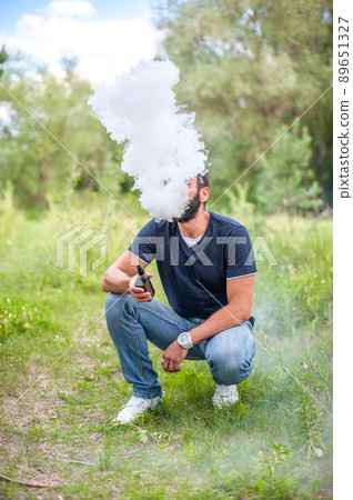 Handsome man smoke electronic cigarette and exhals smoke cloud. Vape. Handsome man smoke electronic cigarette and exhals smoke cloud. Vape. 89651327
