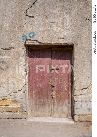 Broken wooden door on grunge stone bricks wall in abandoned street Broken wooden door on grunge stone bricks wall in abandoned street 89652172