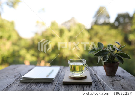 Green tea and Hoya Carnosa with notebook and pencil on wooden table 89652257