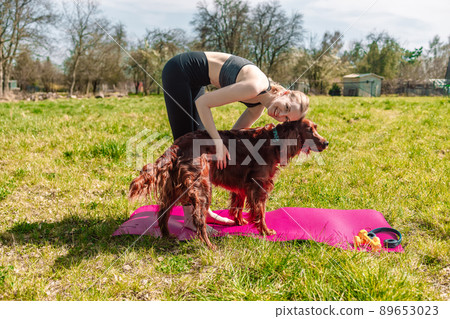 Yoga. Young woman practicing yoga or stretching with big happy Irish Setter dog in nature at park. Yoga. Young woman practicing yoga or stretching with big happy Irish Setter dog in nature at park. 89653023