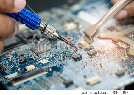 Technician repairing inside of printed circuit board PCB by soldering iron. Integrated Circuit. the concept of data, hardware, technician and technology. 89653924