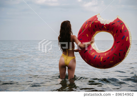 slender girl with a sexy booty in a swimsuit holds an inflatable circle in her hands in the summer at the sea slender girl with a sexy booty in a swimsuit holds an inflatable circle in her hands in the summer at the sea 89654902