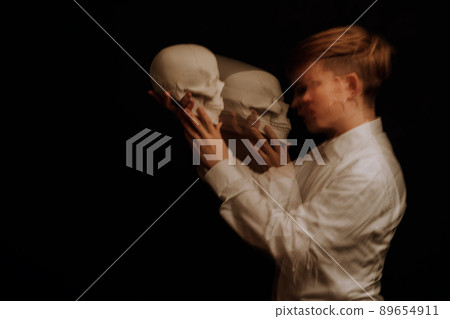 woman is a psychopath with schizophrenia and mental disorders. Portrait of paranoid girl with skull in her hands woman is a psychopath with schizophrenia and mental disorders. Portrait of paranoid girl with skull in her hands 89654911
