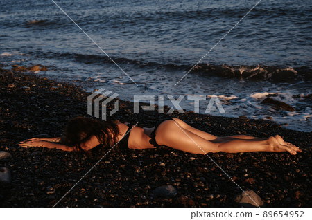 sexy ass of girl with a slender body resting lying on beach by the sea in summer 89654952