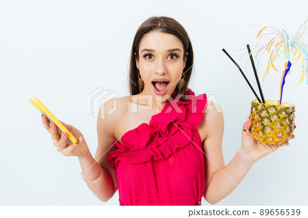 Surprised young woman with pineapple cocktail 89656539