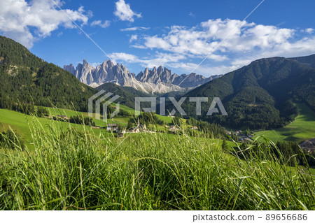 Green grassy meadows in the village of Santa Maddalena against the great peaks of the Odle Group, Val di Funes, Dolomites. 89656686