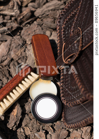 Wax and brush, leather maintenance concept. old genuine leather bag on a background. Wax and brush, leather maintenance concept. old genuine leather bag on a background. 89656941
