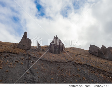 On the tops of the mountains under the cloudy sky are huge sharp stone battlements. Magmatic pyramids. The consequences of the ancient eruption of the Elbrus volcano On the tops of the mountains under the cloudy sky are huge sharp stone battlements. Magmatic pyramids. The consequences of the ancient eruption of the Elbrus volcano 89657548