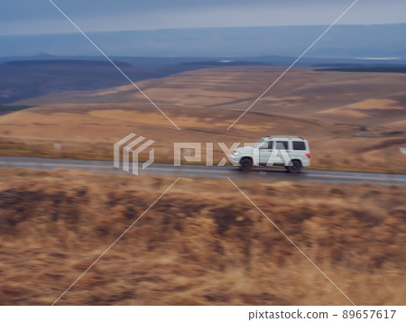 SUV rides on the road surrounded by autumn fields and hills. Blurred image. North Caucasus landscape.Blurred image 89657617
