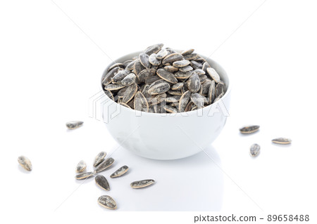 White bowl of sunflower seeds isolated on white background. 89658488