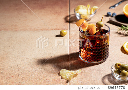 Vermouth cocktail with appetizer isolated on red background with copy space. Typical spanish appetizer. Vermouth cocktail with appetizer isolated on red background with copy space. Typical spanish appetizer. 89658778