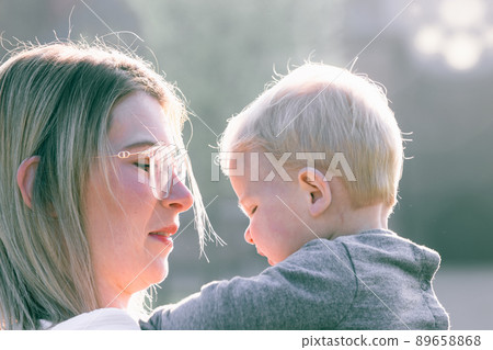 a young happy mother with a small child in her arms, looking at him with adoration and love, stands a young happy mother with a small child in her arms, looking at him with adoration and love, stands 89658868
