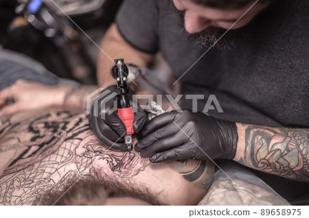 Tattooer makes tattoo in salon 89658975
