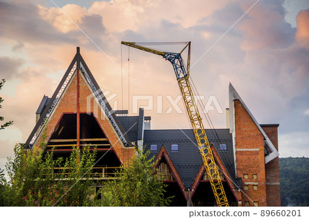 construction site with crane and unfinished cottage in Ukrainian Carpathian village construction site with crane and unfinished cottage in Ukrainian Carpathian village 89660201