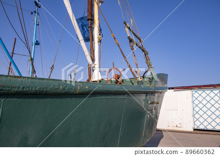 Green boat with red steering wheel and white mastrybatskaya green boat on the seafront. 89660362