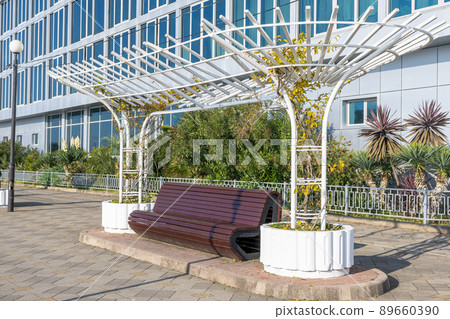 Dark brown wooden bench under a canopy on a sunny day. 89660390