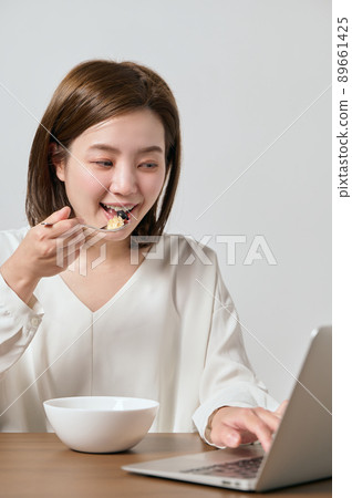 A young vegan woman eating oatmeal while teleworking 89661425