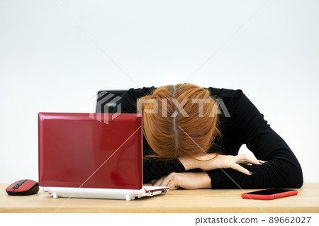 Tired office worker woman having a nap behind working desk. 89662027