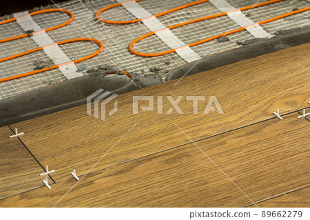 Installation of ceramic tiles and heating elements in warm tile floor. Renovation and improvement concept. 89662279