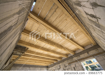 Close-up detail of house room interior under construction and renovation. Energy saving walls of hollow foam insulation blocks, wooden ceiling beams for roof frame. 89663775