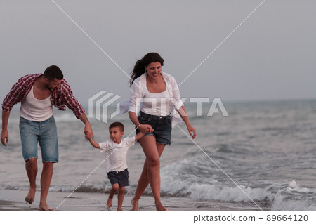 The family enjoys their vacation as they walk the sandy beach with their son. Selective focus  89664120