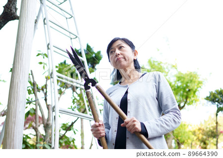 A troubled woman with pruning shears in front of a garden ladder A troubled woman with pruning shears in front of a garden ladder 89664390