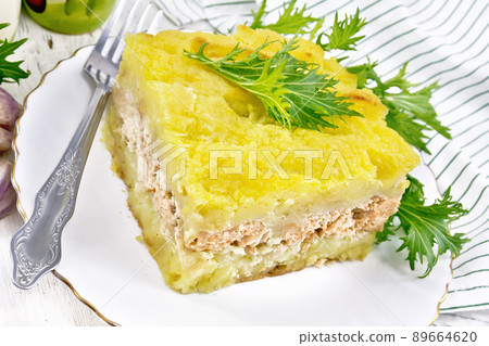 Casserole with potatoes and fish in plate on light wooden board Casserole with potatoes and fish in plate on light wooden board 89664620