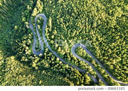 Aerial view of winding road in high mountain pass trough dense green pine woods. Aerial view of winding road in high mountain pass trough dense green pine woods. 89665385