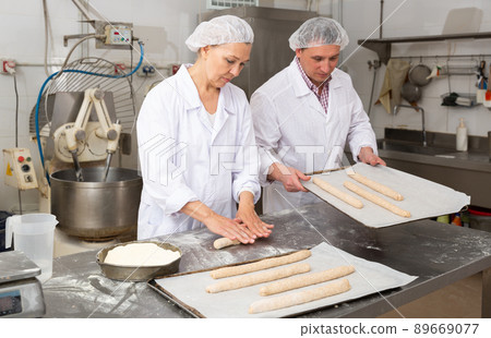 Bakery worker preparing raw baguette dough for baking 89669077