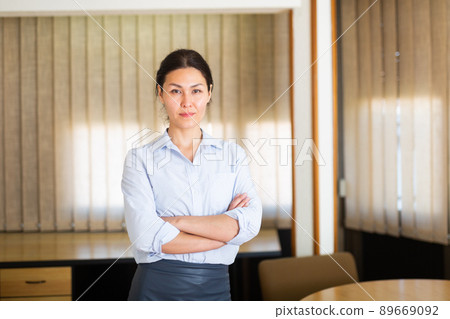 Successful business woman standing with arms crossed in office Successful business woman standing with arms crossed in office 89669092