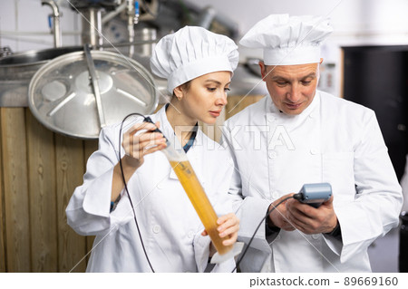 Man and woman brewmasters measuring beer with alcoholometer 89669160