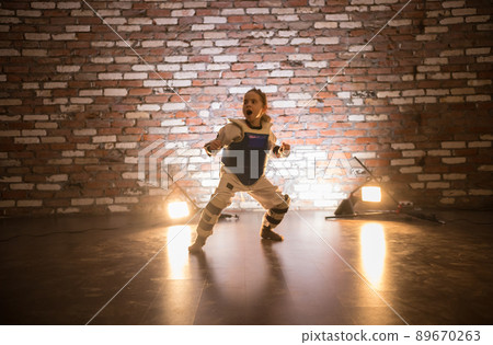 Karate training in the studio. A little girl standing in karate position. Face expression Karate training in the studio. A little girl standing in karate position. Face expression 89670263