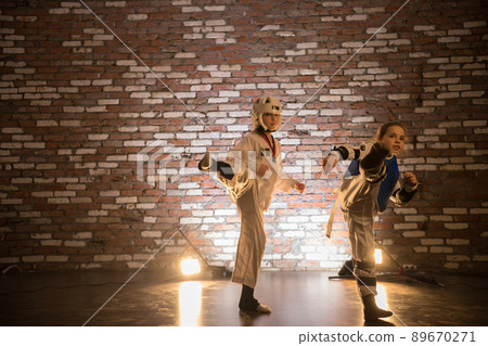 Karate training in the studio. Two little girls training karate skills. Attack with a leg 89670271