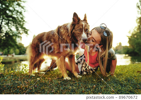 Close up portrait of young woman kissing her dog in the park Close up portrait of young woman kissing her dog in the park 89670672