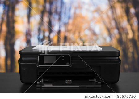 Compact laser printer on black desk against blurred background Compact laser printer on black desk against blurred background 89670730