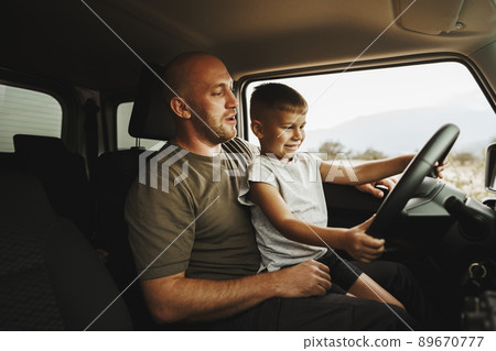 Father teaches little son to drive on road trip 89670777