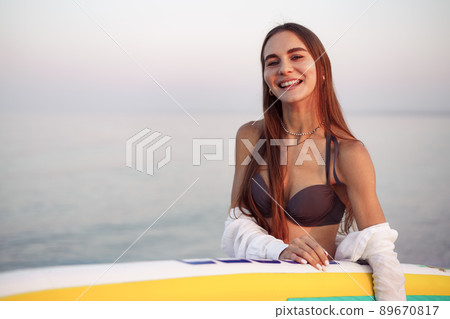Young woman is carrying paddle board at the beach 89670817