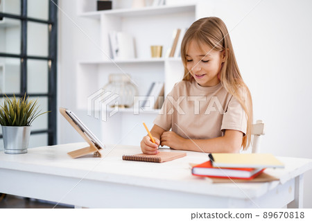 Teenage girl making notes in notepad, doing homework at table at home 89670818