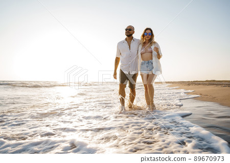 Young beautiful couple walking on beach near sea 89670973