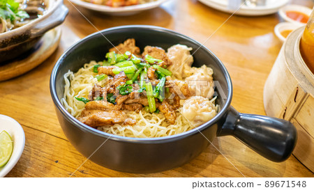Egg noodle with stir fried garlic pork, a close up of Thai dry noodles on woodle table at Thai food restaurant background in Bangkok, Thailand Egg noodle with stir fried garlic pork, a close up of Thai dry noodles on woodle table at Thai food restaurant background in Bangkok, Thailand 89671548