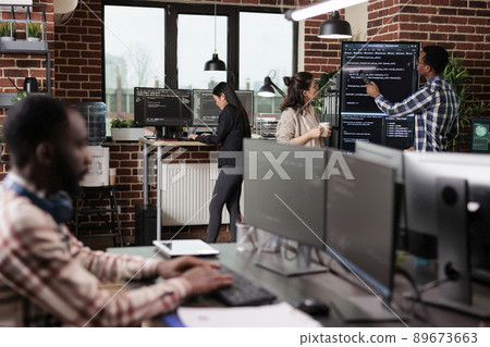 Tech engineers team leader pointing out mistake in application source code. Software developers standing near vertical screen talking about interface bug and slow rate of processing data. 89673663