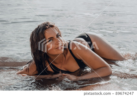 Elegant woman lies on water. Sunset and silhouette. The concept of unity with nature. 89674247