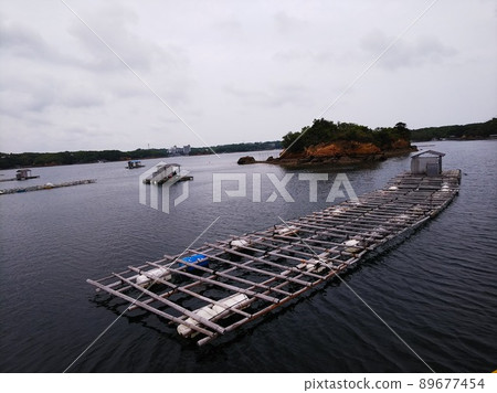 內海一個小島附近的漁筏和小小屋,海浪平靜 內海一個小島附近的漁筏和小小屋,海浪平靜 89677454