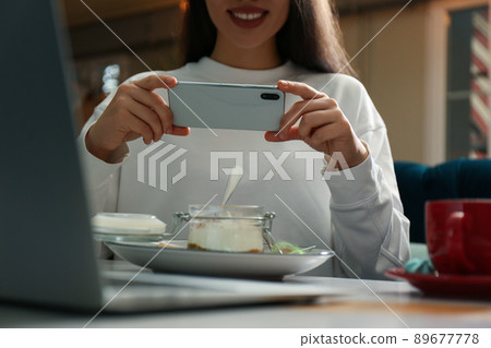 Blogger taking picture of dessert at table in cafe, closeup Blogger taking picture of dessert at table in cafe, closeup 89677778