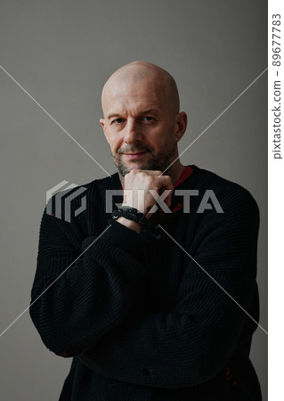 Vertical medium studio portrait of confident mature Caucasian man wearing black sweater looking at camera, gray background Vertical medium studio portrait of confident mature Caucasian man wearing black sweater looking at camera, gray background 89677783