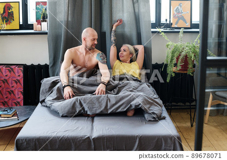 Modern mature Caucasian man and woman in love waking up together in loft bedroom in morning Modern mature Caucasian man and woman in love waking up together in loft bedroom in morning 89678071